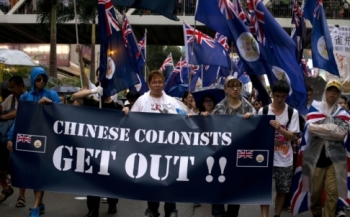 Protesters rallying for democracy on July 1, 2013 carry British-era Hong Kong flags and a banner: "Chinese Colonists Get Out!!" to demand democratic reforms (Photo: AFP. Source: South China Morning Post)